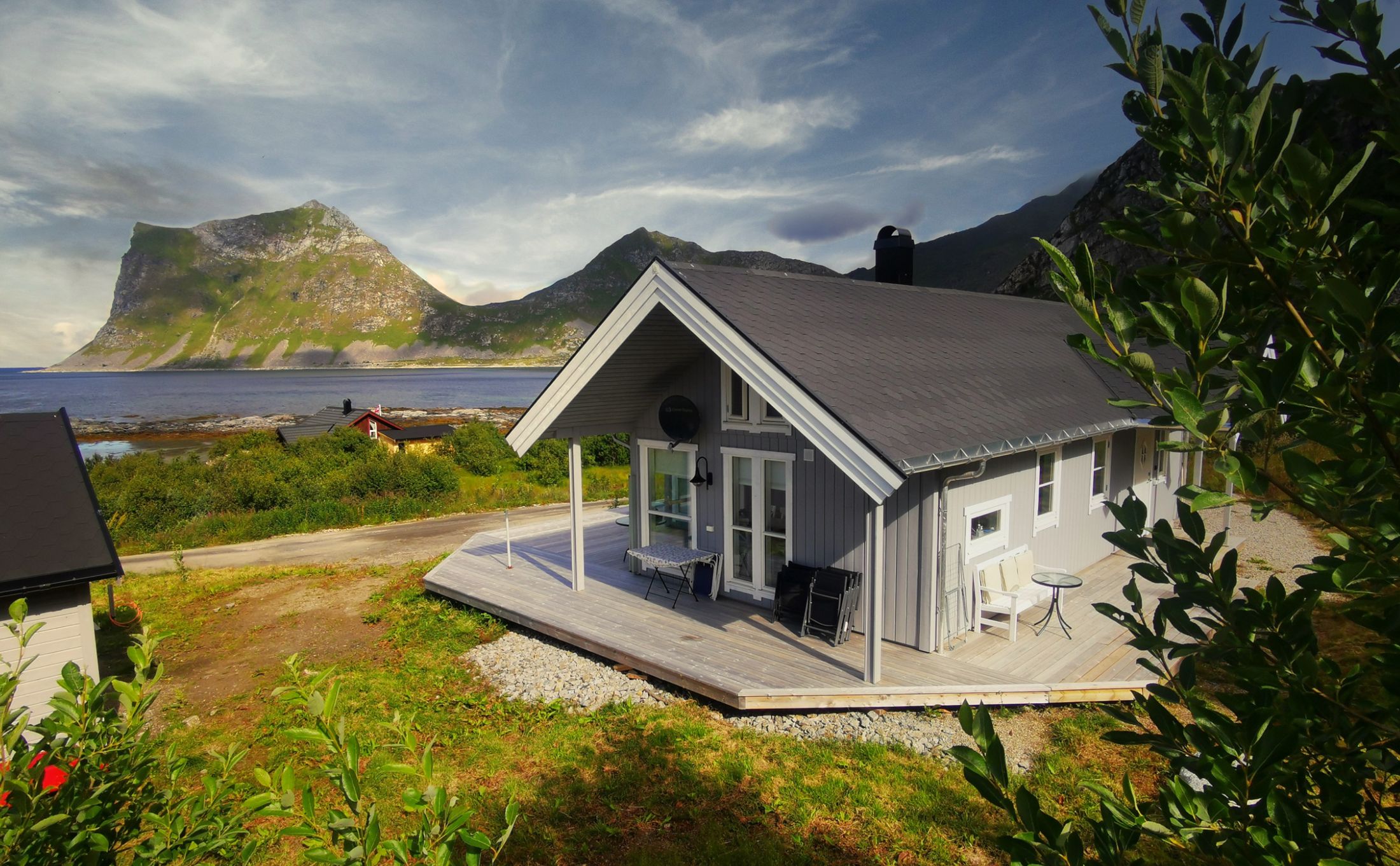 Cabin Panorama in summer, with the terrace and the mountains by the sea behind